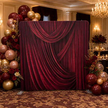 Event room decorated with velvet red draped curtain backdrop and balloons