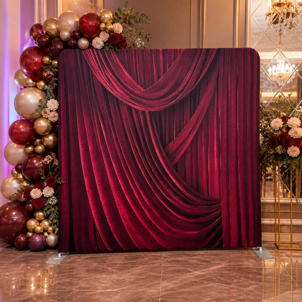 Photo booth setup with velvet red draped curtain backdrop and floral balloon decor