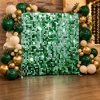 Party setting with shimmering green sequin fabric backdrop surrounded by green, white and gold balloons